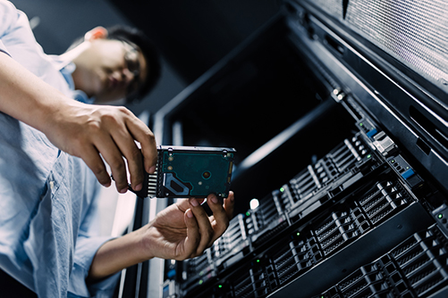 An it expert examines storage media while maintaining a server farm.